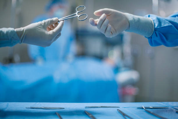 mãos de enfermeira passando ferramenta médica para médico usando roupa de trabalho protetora em sala de cirurgia médica no hospital com paciente incidental pessoas antecedentes - nurse reaching women doctor - fotografias e filmes do acervo