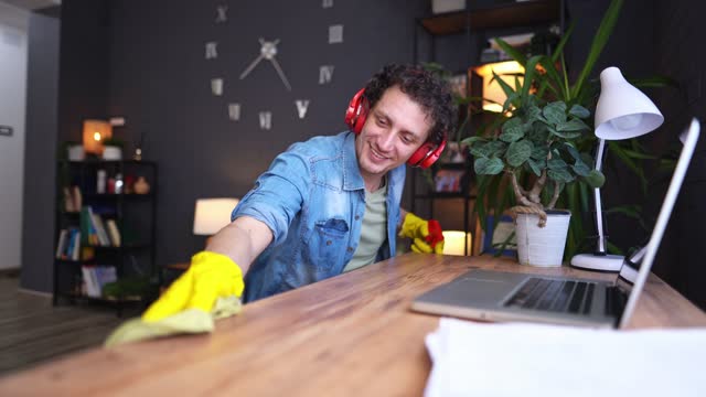 Men listening to music while cleaning his work desk