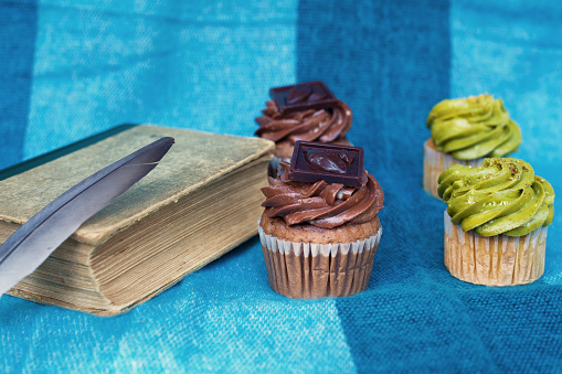 Still life with an old book, cupcakes and a feather