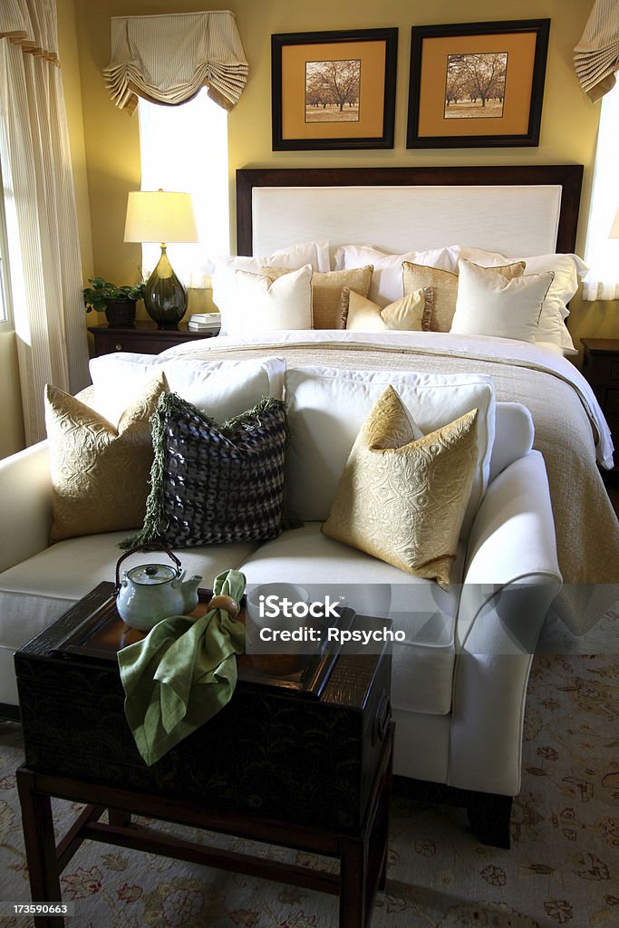 Bedroom Luxury "A beautifully decorated bedroom, bathed in soft morning sunlight, with lots of big fluffy pillows, a love seat, and a breakfast table. View other" Architecture Stock Photo