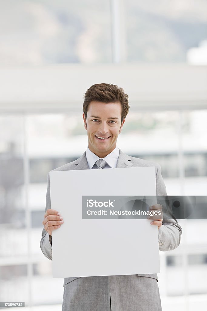 Hombre de negocios joven feliz sosteniendo una tarjeta en blanco, blanco - Foto de stock de 20-24 años libre de derechos