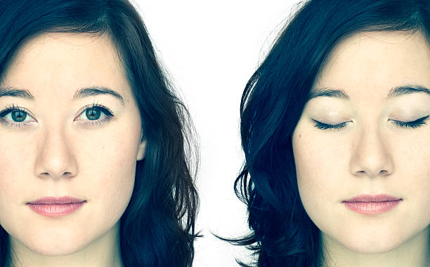 Identical twins posing, one with eyes open, the other closed stock photo