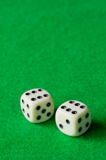 Pair of dice, both showing six, against a green background. Space for copy.