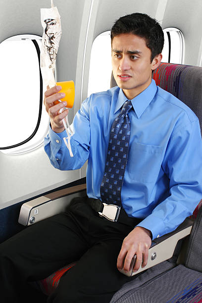 Panic In The Sky Passenger on a commercial airliner putting on an oxygen mask. oxygen mask plane stock pictures, royalty-free photos & images