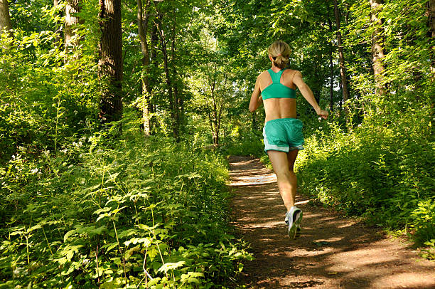 Woman Running On Forest Trail stock photo
