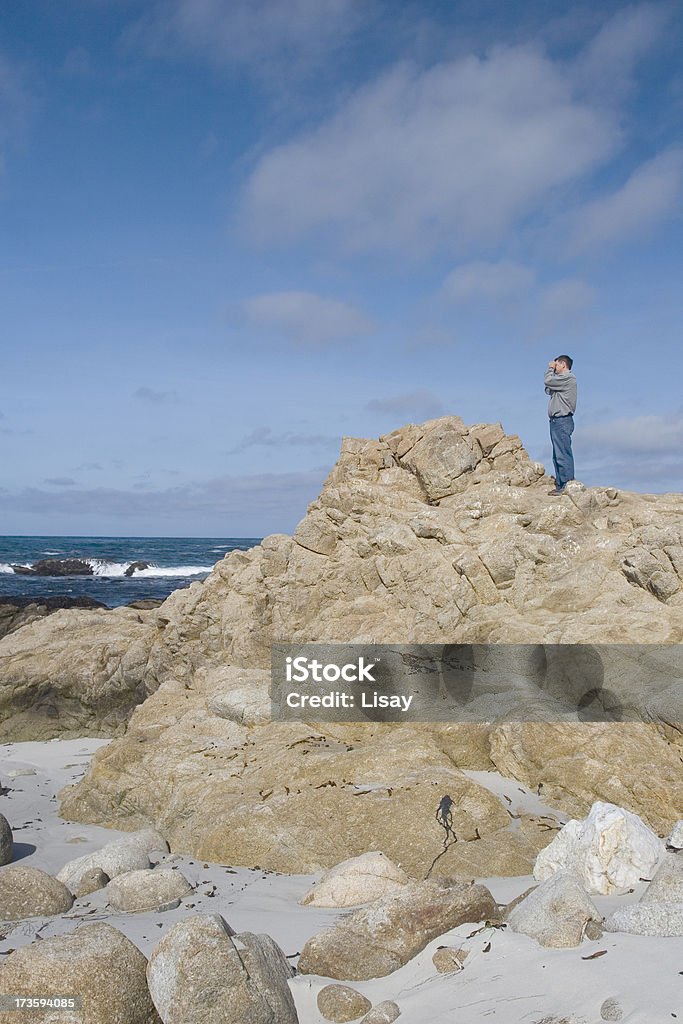 Man Looking at Ocean A man stands on a rock looking out over the ocean. Adult Stock Photo