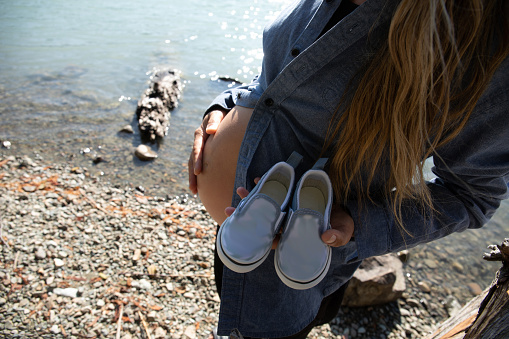 She holds a pair of blue shoes to indicate male gender. At Green Lake, in Whistler, BC.