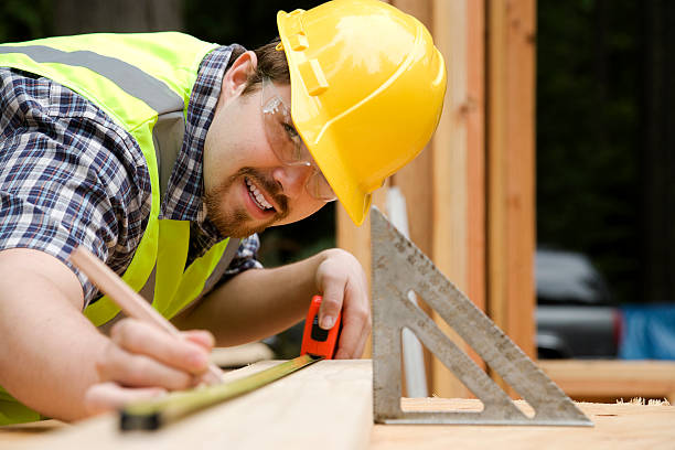 istock Man wearing hard hat and reflector jacket measuring wood 173595805