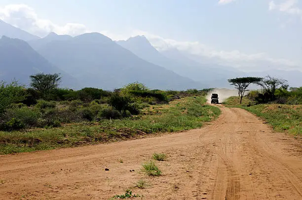 A Landrover driving along a dirt road in the African wilderness.