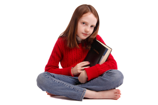 Beautiful little girl holding the Bible on a white background