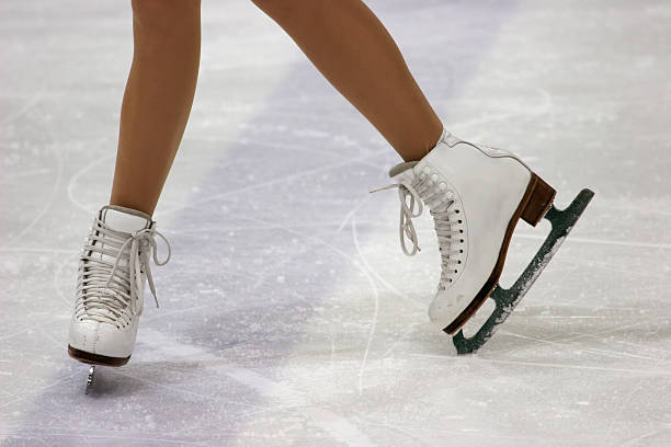 Close up of figure skaters feet in skates on ice stock photo