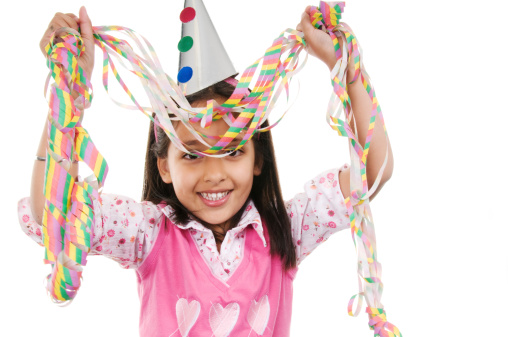 Young girl with party hat and streamers.