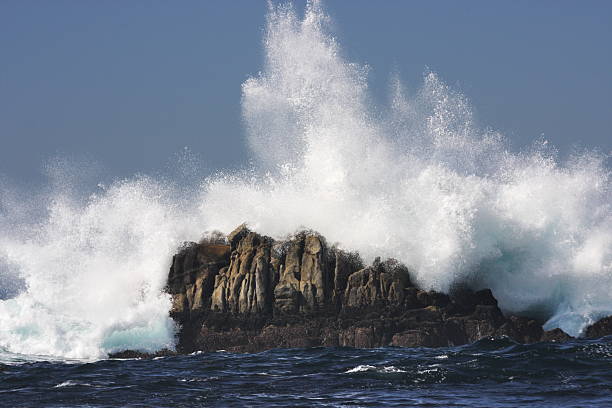 Ocean Wave Crashes Rock Coast Surf Spray Pacific surf slams beach rock sending white spray high into blue sky.  Pacific Grove, California, 2008. mavericks california stock pictures, royalty-free photos & images