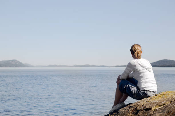 Jeune femme qui donne sur l'eau - Photo