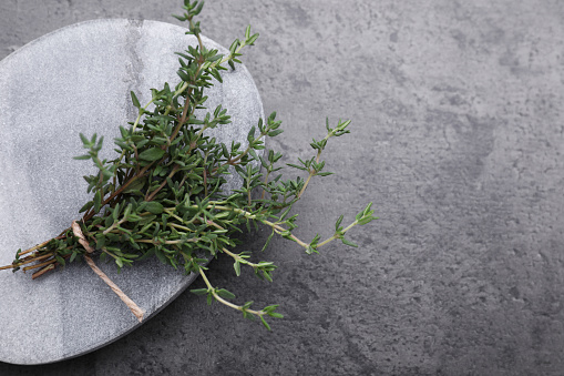 Bunch of fresh thyme on grey table, top view. Space for text