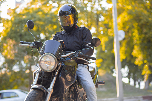 motorcyclist on a classic street motorcycle in a motorcycle jacket and helmet with sun protection.