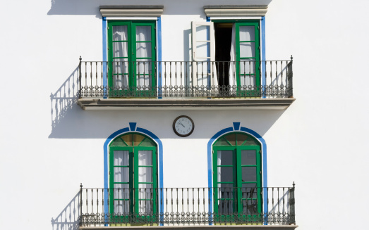 white facade with blue green windows and two balconys