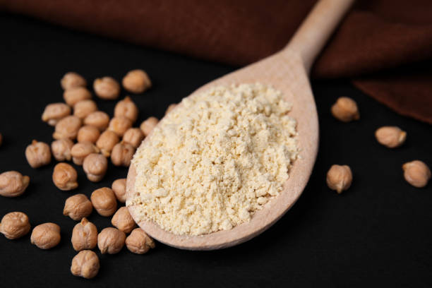 istock Spoon with chickpea flour and seeds on black table, closeup 1735994912