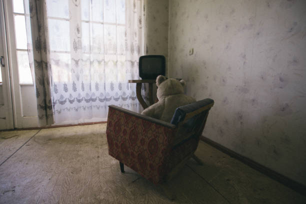 istock Old Teddy bear sitting on chair and watching TV 1735996496