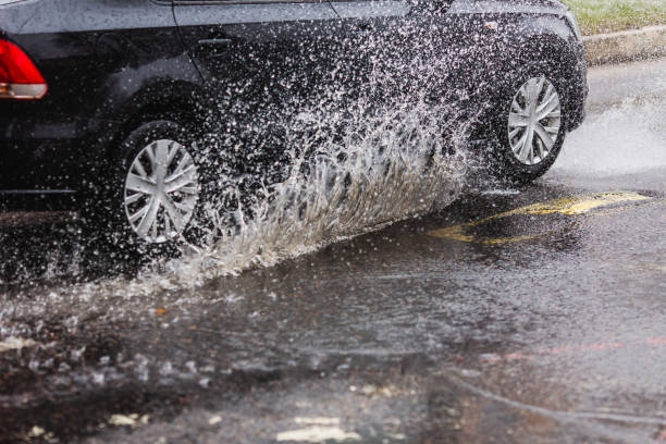 wasserspritzer aus fahrendem auto. pfütze auf der straße. regenwetter. regen. - skidding car tire rain stock-fotos und bilder