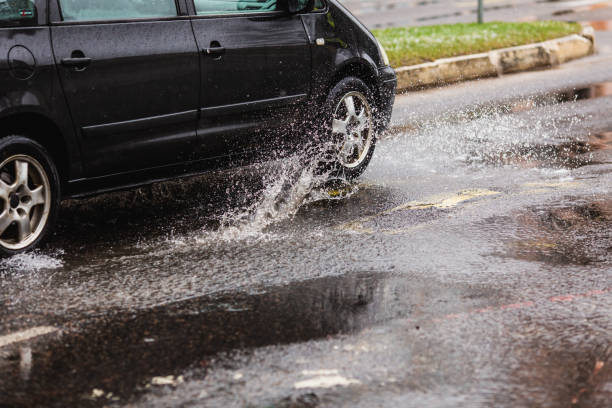 wasserspritzer aus fahrendem auto. pfütze auf der straße. regenwetter. regen. - skidding car tire rain stock-fotos und bilder