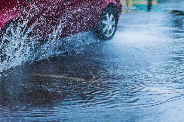 wasserspritzer aus fahrendem auto. pfütze auf der straße. regenwetter. regen. - skidding car tire rain stock-fotos und bilder