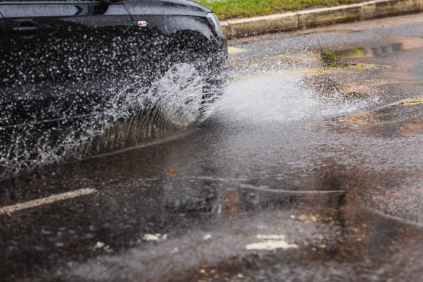 wasserspritzer aus fahrendem auto. pfütze auf der straße. regenwetter. regen. - skidding car tire rain stock-fotos und bilder