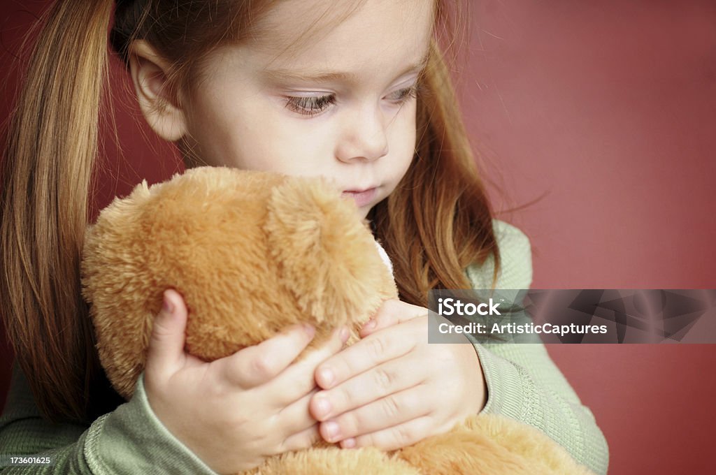 Triste petite fille tenant son ours en peluche - Photo de Affolé libre de droits