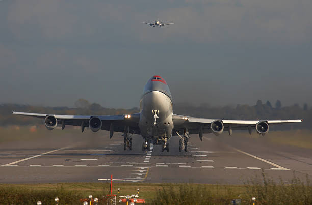 Head on photo of a large widebody airplane at take off with another airliner behind about to land.