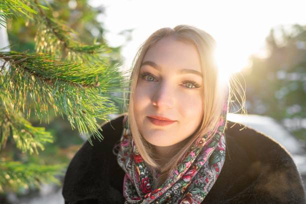 Portrait of a woman in a headscarf and a black fur coat in a winter forest close-up.