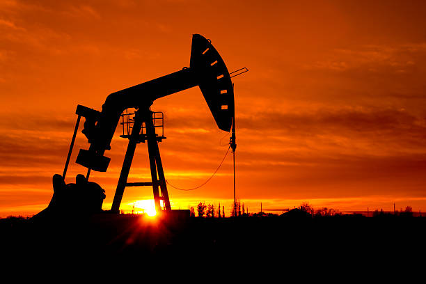 Pumpjack as the sunrises A pumpjack silhouetted against a sunrise.  Part of a series of the same pumpjack oil pump oil industry alberta equipment stock pictures, royalty-free photos & images