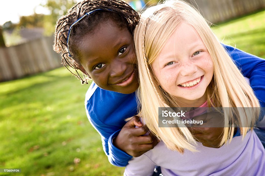 Zwei kleine Mädchen Lächeln und Reiten draußen Huckepack nehmen - Lizenzfrei Kind Stock-Foto