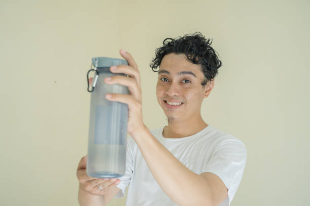 istock Curly man hold hold and show the bottle mineral. 1736052483