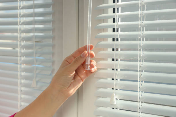 istock Woman opening horizontal blinds on window indoors, closeup 1736055578