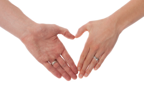 A husband and wife's hands in the shape of a heart.
