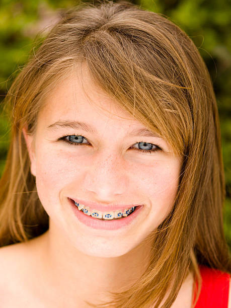 Young girl wearing braces and smiling outdoors stock photo