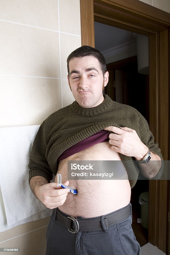 Funny fat man Funny fat man making funny face and inserting razor in to his navel Adult Stock Photo