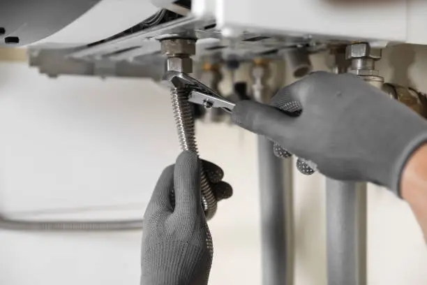 Man repairing gas boiler with waterpump plier, closeup