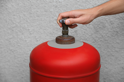 Man opening red gas cylinder near wall, closeup