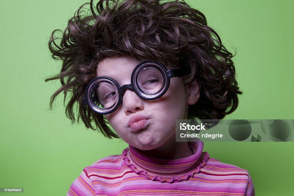 Geek on Green - Suspicious Child with geeky glasses and crazy hair looks suspiciously out of the corner of her eyes. Shot against a green background. 6-7 Years Stock Photo