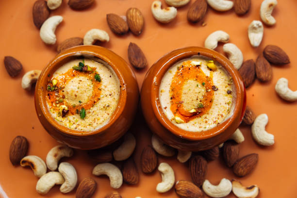 istock Kulfi ice cream in two clay pots on a solid orange background with cashews and almonds. Kulfi is a popular traditional Indian dessert made of milk with spices and nuts 1736097338