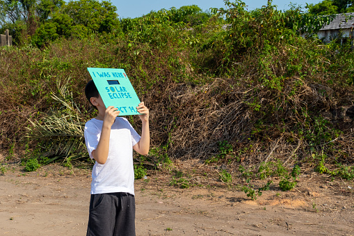 Young boy, age 10, watching the annular solar eclipse across the Americas on october 14, 2023, with his customized protective mask