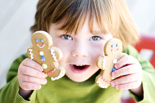 Little boy holding gingerbread man cookies.  Focus on his hands holding the cookies.