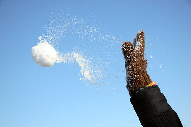 hand throwing a snowball Close up of a gloved hand throwing a snowball. Clear sky in the background. Flying snowball. Tiny ice crystals sputtering away.see other pictures of this series: snowball stock pictures, royalty-free photos & images