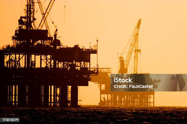 Off Shore Oil Platforms At Sunset Stock Photo - Download Image Now - Offshore Platform, In Silhouette, Sunset