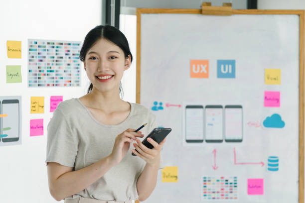 istock Portrait of creative UX UI designer working on screens for mobile responsive website development, focusing on UI UX. Developing wireframe sketch layout designs on a smartphone screen. 1736162105