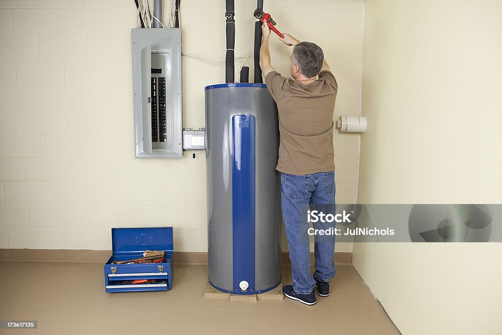 Plumber fixing Water Heater Plumber using a pipe wrench while working on a water heater.Please also see: Boiler Stock Photo