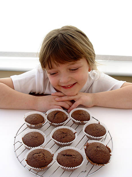 若い女の子 longingly チョコレートケーキをお探しですか - longingly ストックフォトと画像