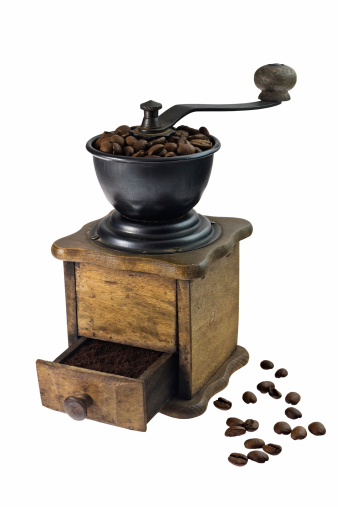 Brown coffee grinder and freshly roasted and grinded coffee beans on white background