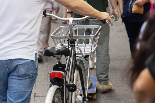 man pushing a bicycle amidst the crowd in a pedestrian area of the city